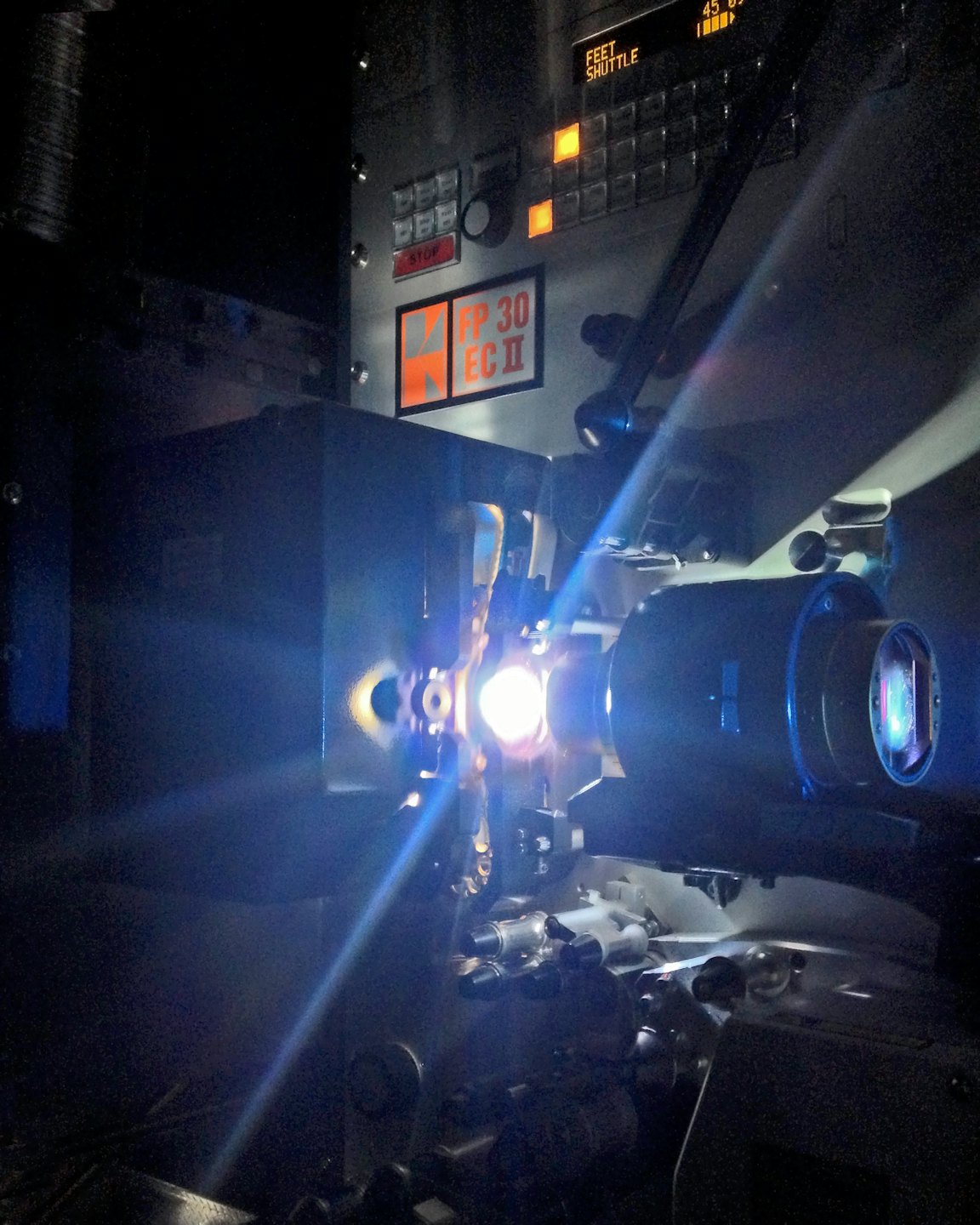 A vintage film projector shines a bright beam of light.