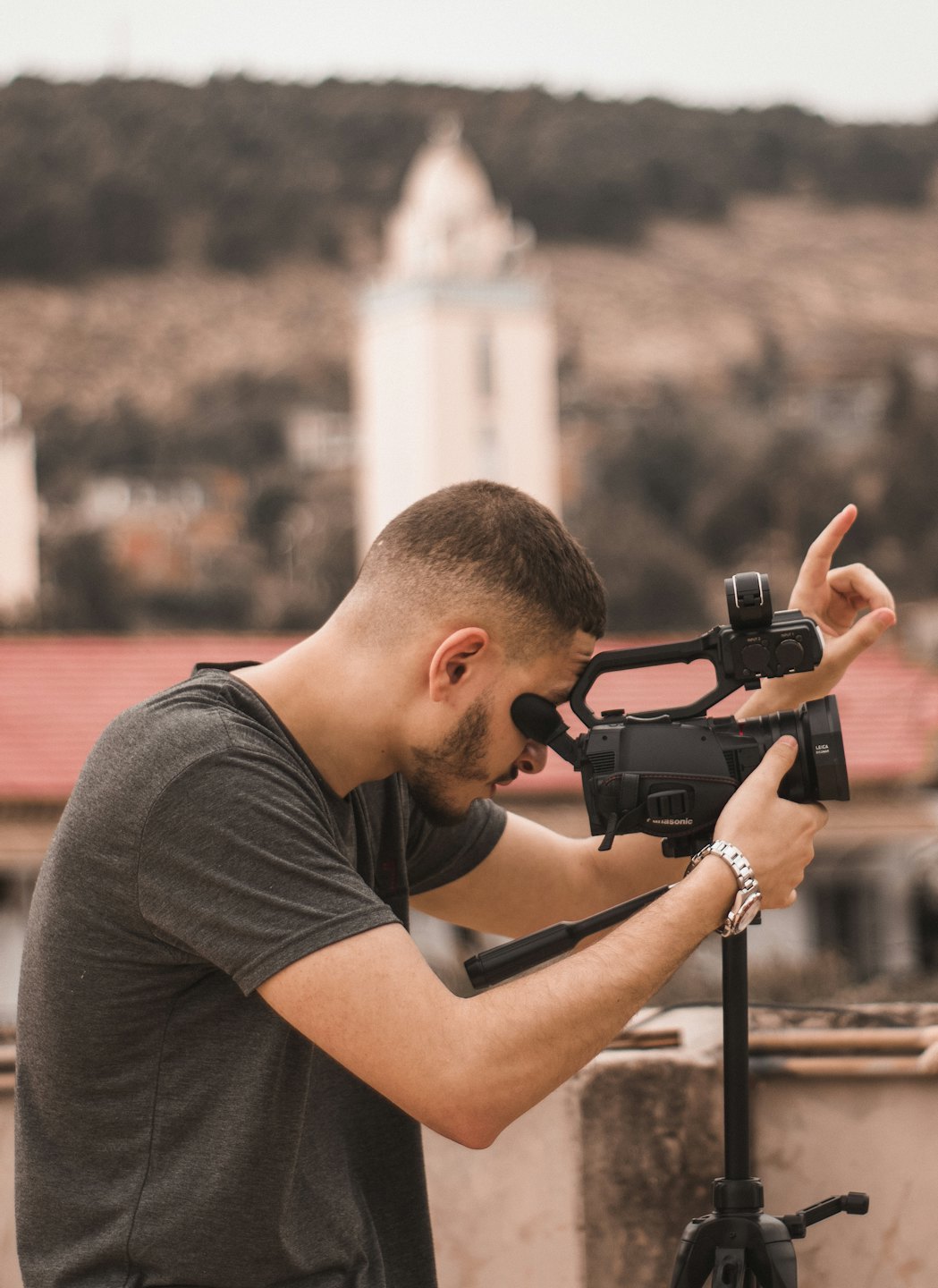 Filmmaker operates a video camera on a rooftop balcony.
